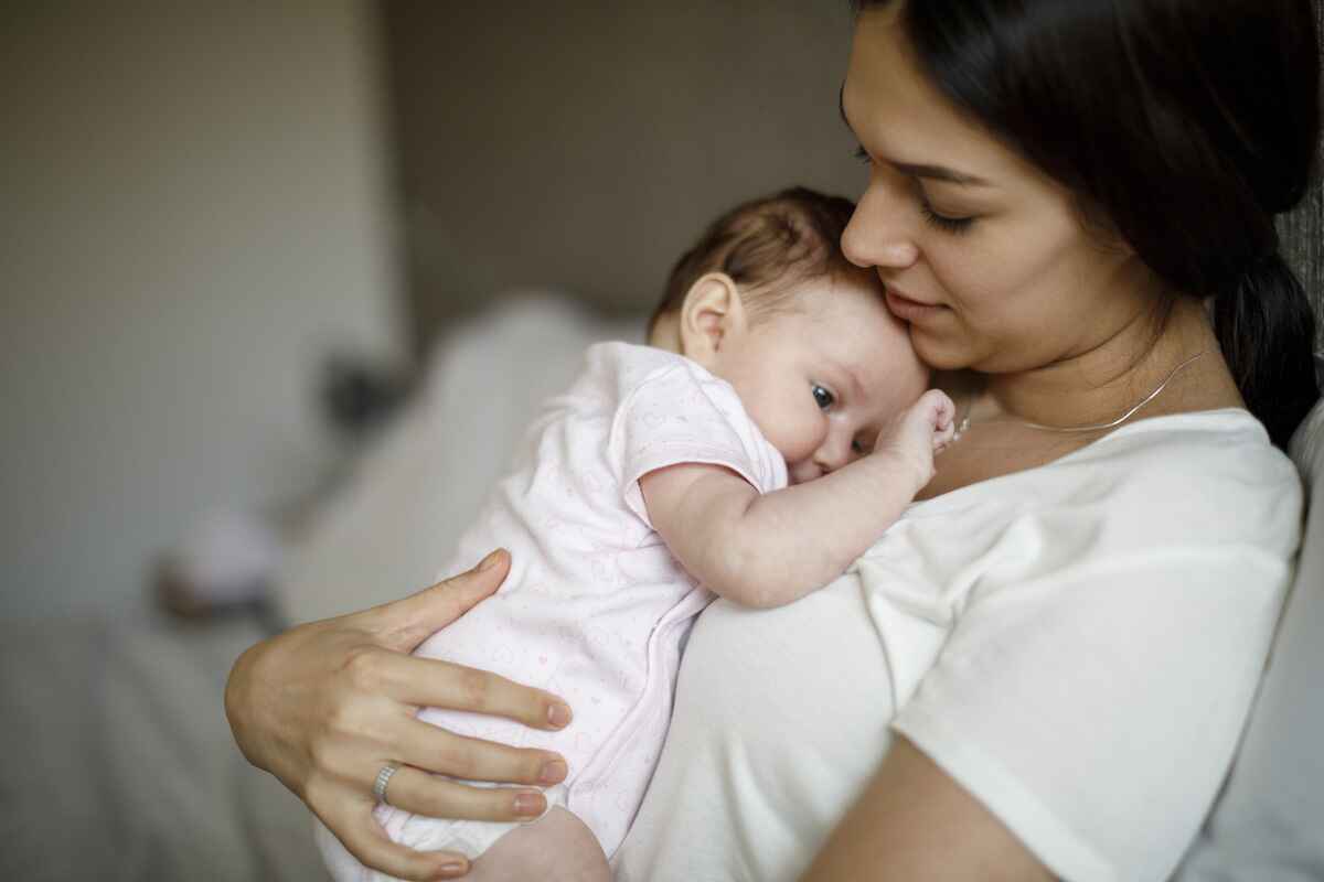 New mother holds her baby thinking about postpartum symptoms