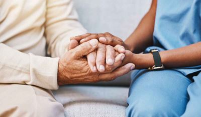 Elderly patient holds hands with doctor
