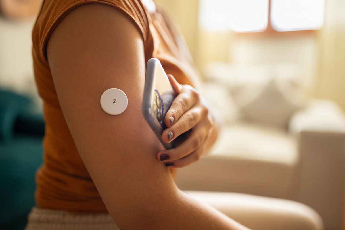 woman uses a continuous blood glucose monitor