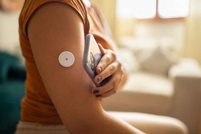 woman uses a continuous blood glucose monitor