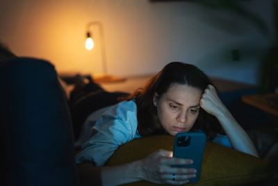a woman scrolling on her phone late at night