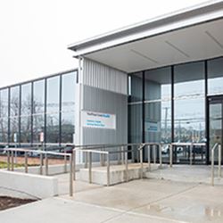 building entrance  with large glass pane and signage, wheelchair ramp, guardrails